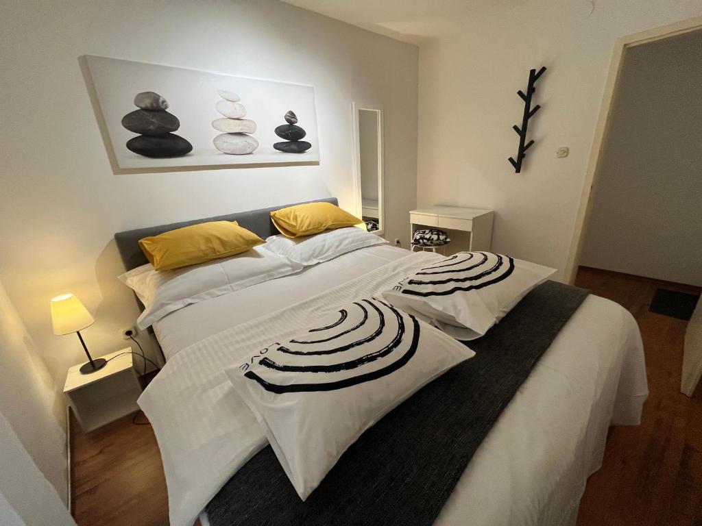 a bedroom with a large bed with white sheets and yellow pillows at Apartman Passagio in Rovinj