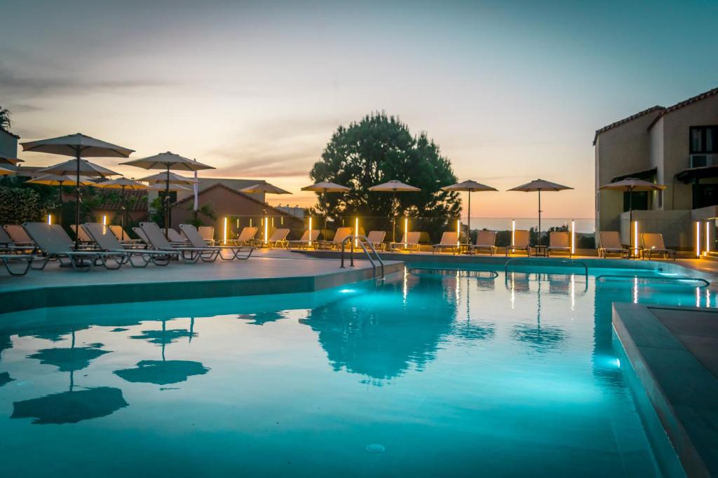 una piscina con sillas y sombrillas en un hotel en Dream Village en Hersonissos