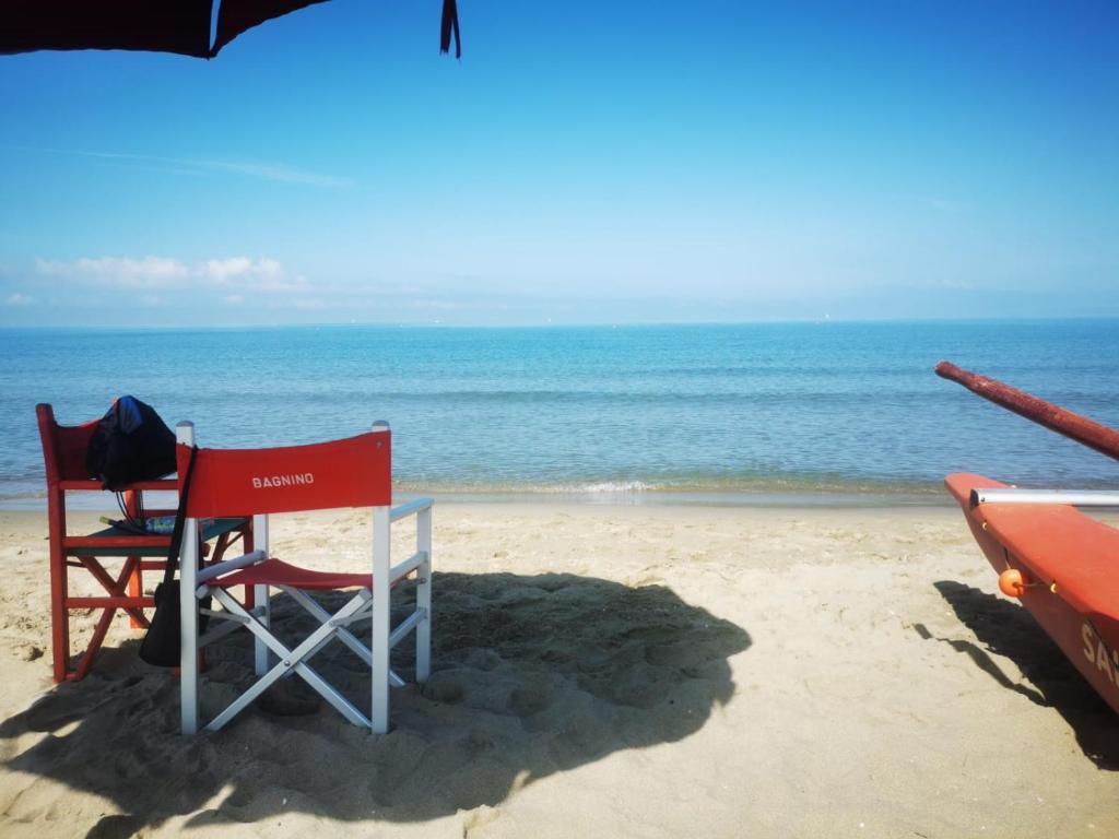 een stoel en een parasol op het strand bij Casa indipendente, 250 m dalla spiaggia in Pisa