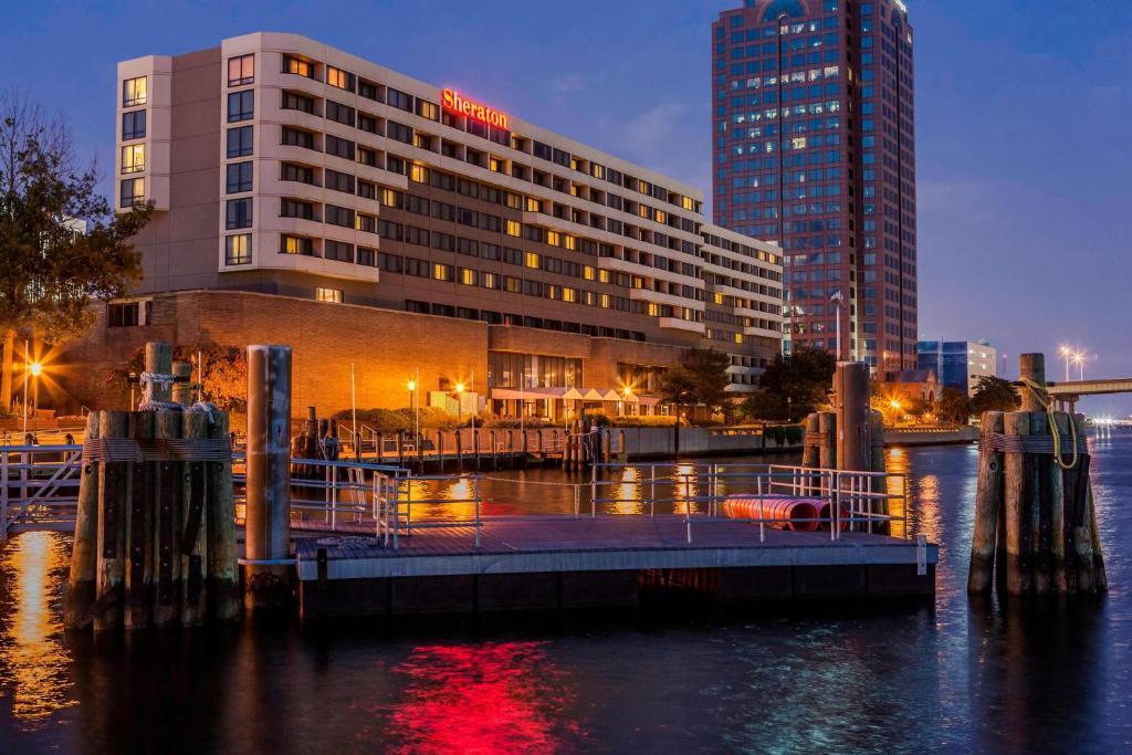 un hotel con un edificio di fronte ad un corpo d'acqua di Sheraton Norfolk Waterside Hotel a Norfolk