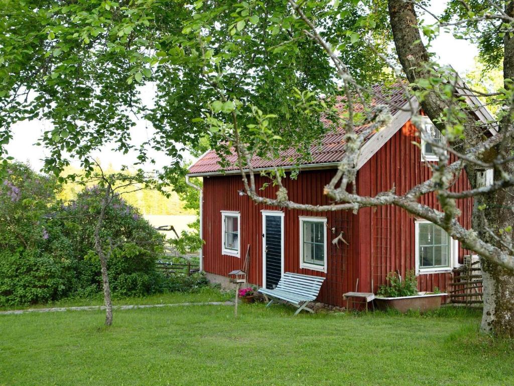 una casa roja con un banco delante en 2 person holiday home in N SSJ, en Nässjö
