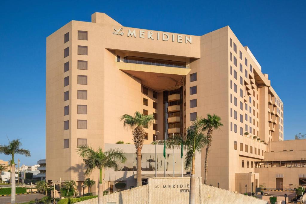 a hotel with palm trees in front of it at Le Meridien Jeddah in Jeddah