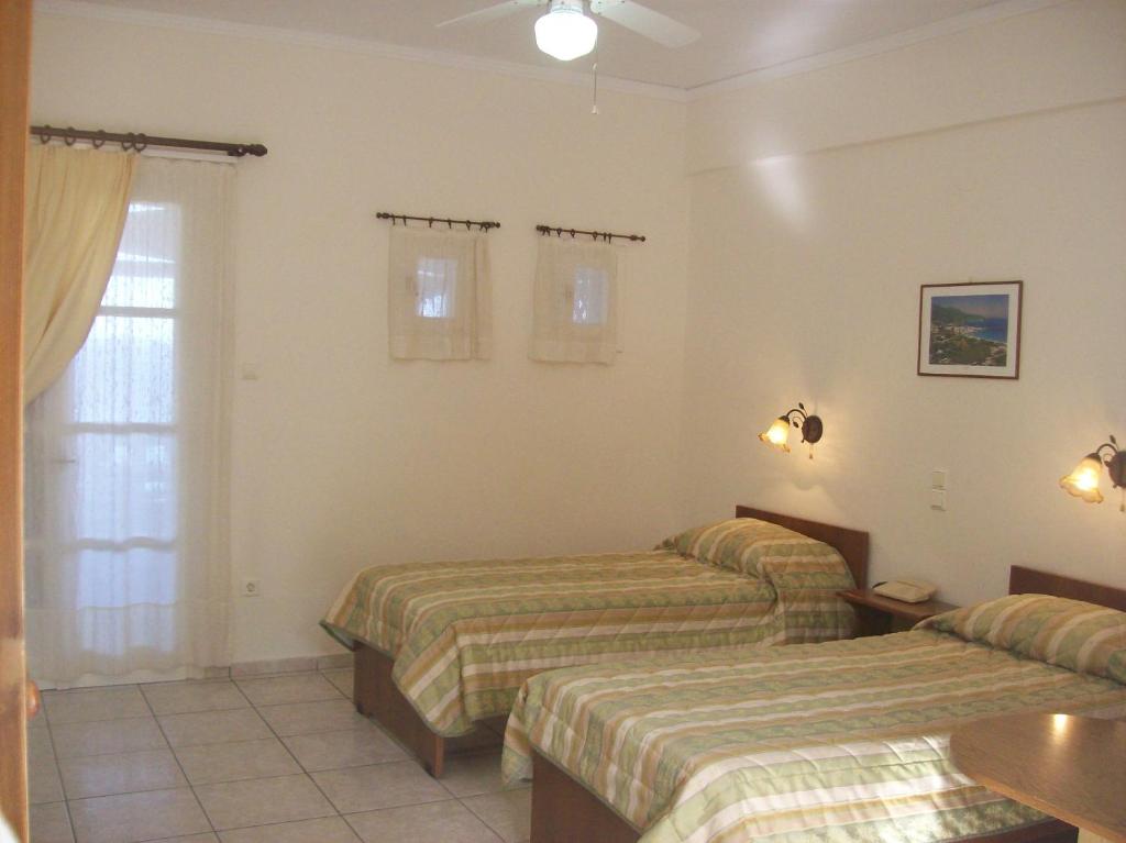 a hotel room with two beds and a window at Vassiliki Studios in Andros