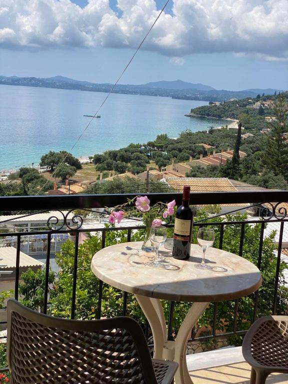 a table with a bottle of wine and glasses on a balcony at Vasiliki see view apartments in Barbati