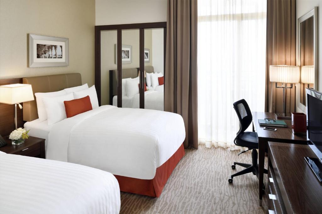 Habitación de hotel con 2 camas y escritorio en Marriott Executive Apartments Riyadh, Convention Center, en Riad