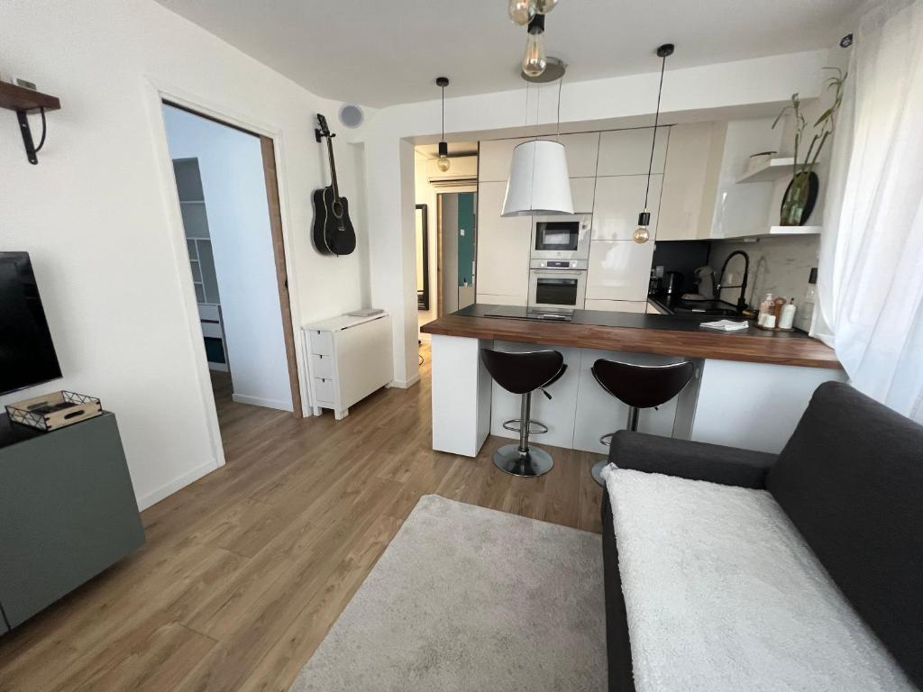 Una sala de estar con un sofá y una cocina. en Appartement 2 chambres en bord de mer 46m2, en Sète