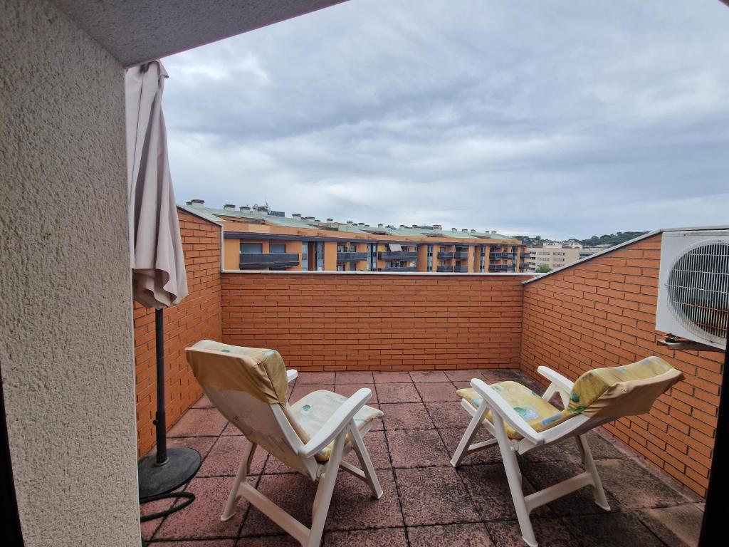 two chairs sitting on a balcony with an umbrella at La playa in Lloret de Mar