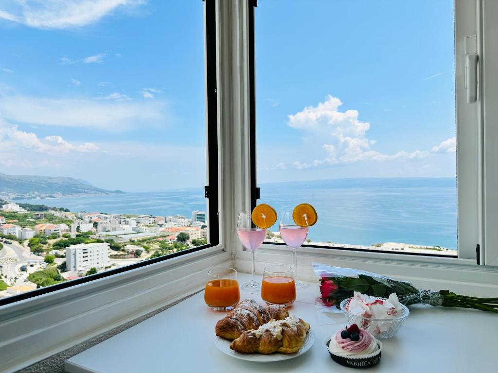 einen Tisch mit zwei Gläsern Orangensaft und Gebäck vor einem Fenster in der Unterkunft T-star, 2-bedroom apartment with magnificent beach view in Split