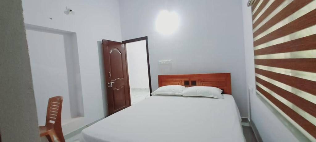 1 dormitorio con cama blanca y cabecero de madera en PADAVAYAL GREENS, en Attappādi
