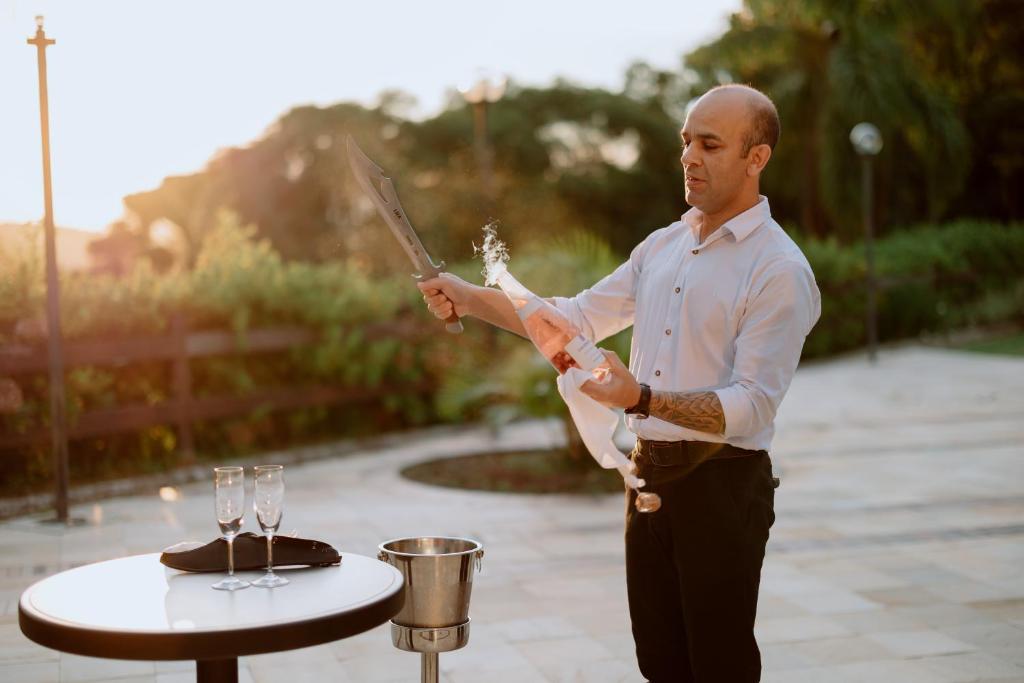 Un uomo che tiene un coltello vicino a un tavolo con una torta di Serra Alta Hotel a São Bento do Sul