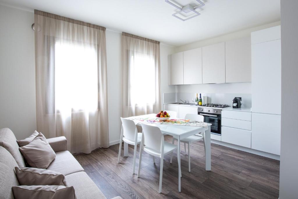 cocina blanca con mesa blanca y sillas en BORGO VERTICALE Luxury Apartments, en Feltre