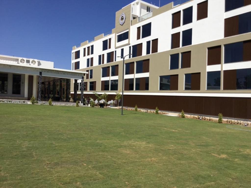 a large building with a grass field in front of it at VRR Astoria Hotel & Convention Center in Bangalore