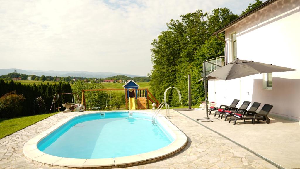 una piscina en un patio con sillas y sombrilla en Sofia Holiday Haven in Nature with Pool en Slovenska Bistrica