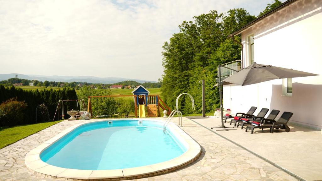 einen Pool auf einer Terrasse mit Stühlen und einem Sonnenschirm in der Unterkunft Sofia Holiday Haven in Nature with Pool in Slovenska Bistrica