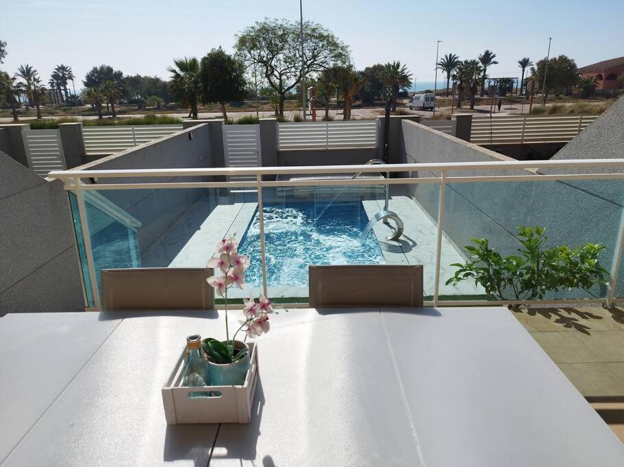 balcón con mesa y piscina en Villa de lujo frente al mar, en Barrio-Mar