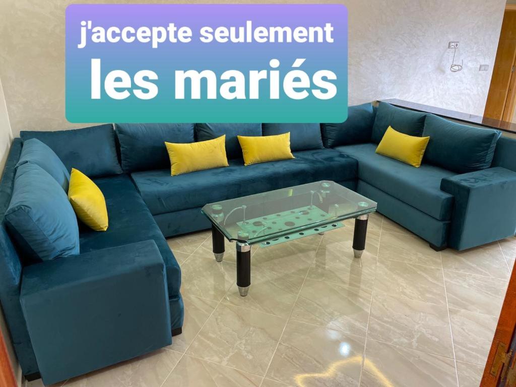 a blue couch with yellow pillows and a coffee table at Appartement pour famille avec enfant in Al Hoceïma