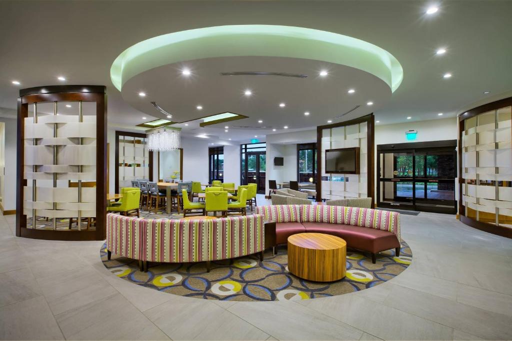 a lobby with a waiting area with tables and chairs at SpringHill Suites by Marriott Wilmington Mayfaire in Wilmington