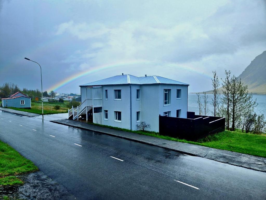 a rainbow over a white house on a street at Sólgarður Guesthouse in Bíldudalur