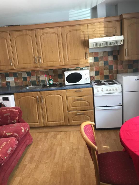 een keuken met houten kasten en een witte kookplaat bij City centre apartments free Wi-Fi free parking in Derry Londonderry