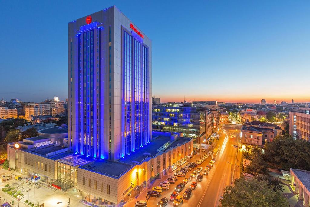 un grand bâtiment avec des lumières bleues sur lui dans une ville dans l'établissement Sheraton Bucharest Hotel, à Bucarest