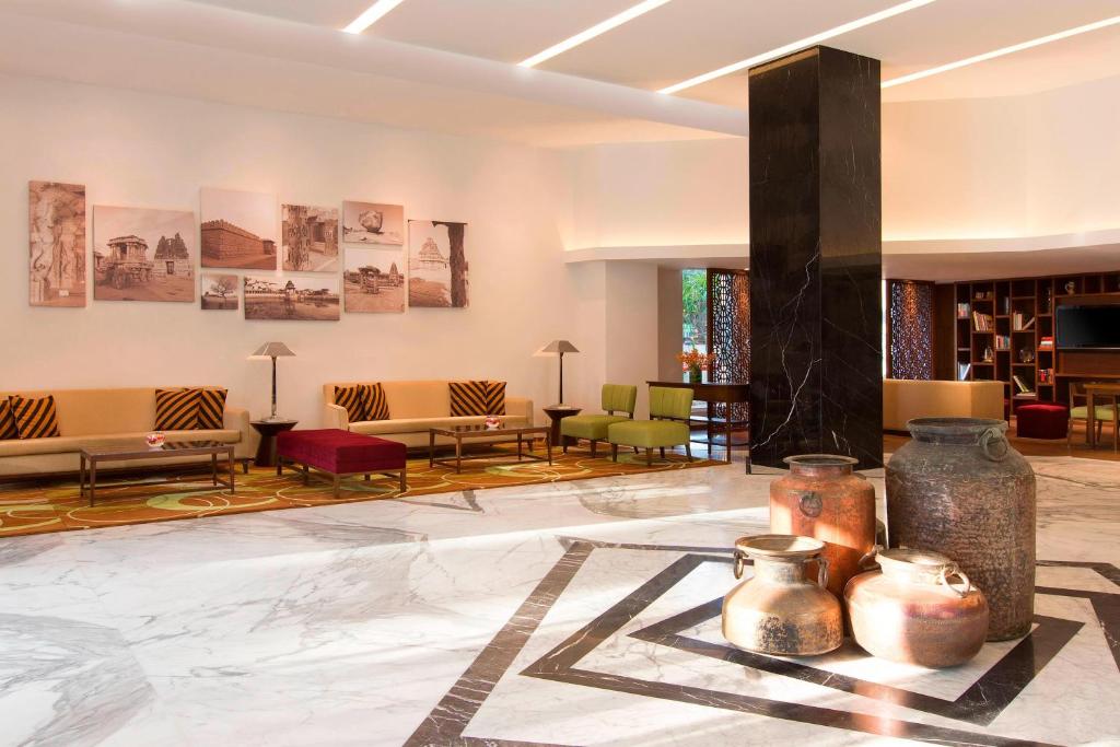 a lobby with tables and chairs in a building at Four Points by Sheraton Bengaluru Whitefield in Bangalore