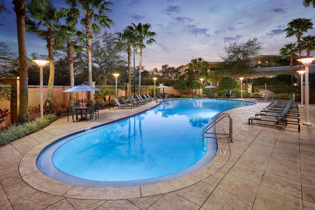 una gran piscina con sillas, mesas y palmeras en Orlando Marriott Lake Mary, en Lake Mary