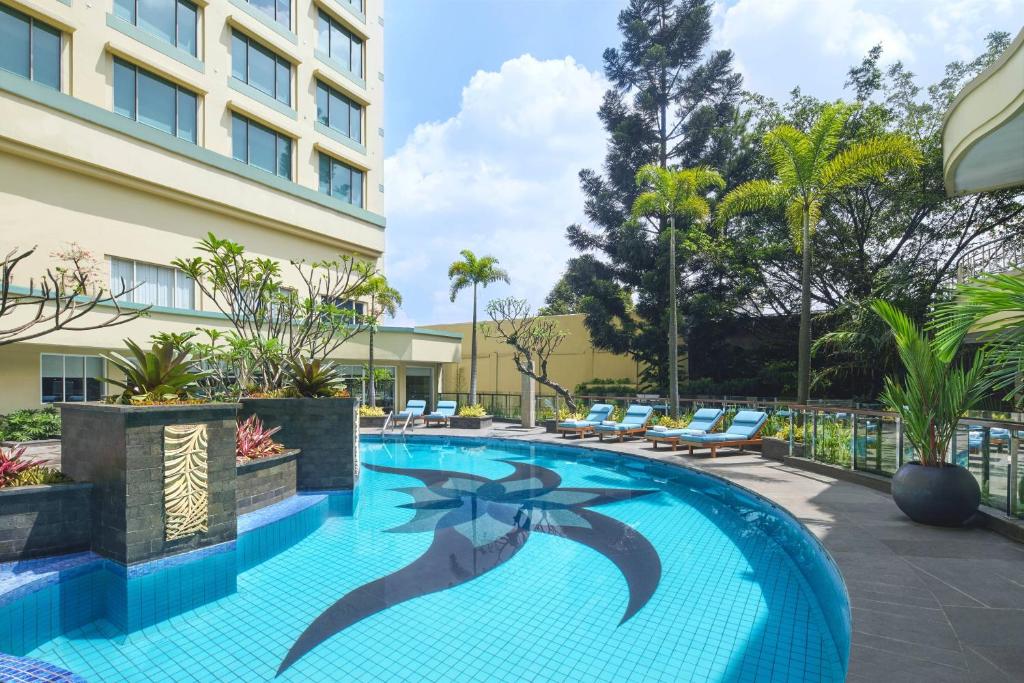 Courtyard by Marriott Bandung Dago في باندونغ: مسبح في فندق فيه كراسي ومبنى