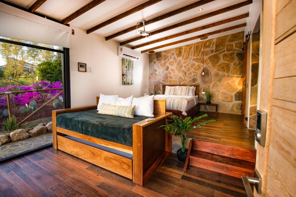 a bedroom with a bed and a stone wall at Brisa Del Valle Hotel Boutique in Valle de Guadalupe