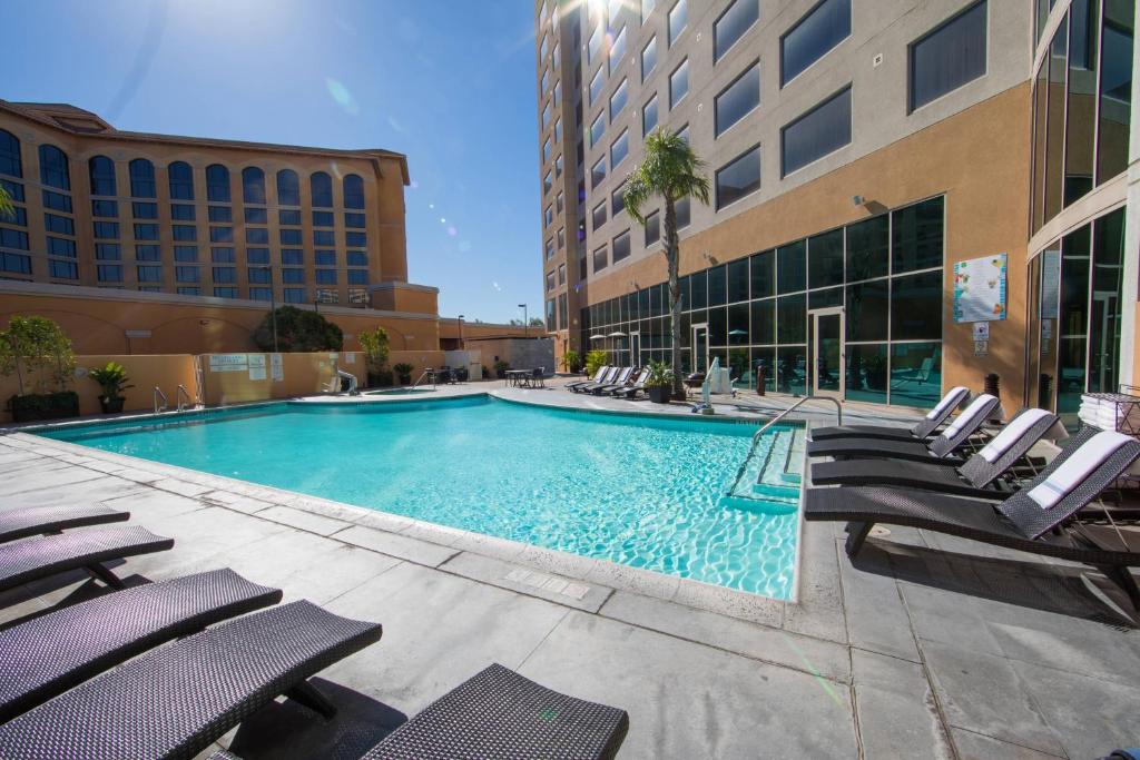 une grande piscine avec des chaises et un bâtiment dans l'établissement Anaheim Marriott Suites, à Anaheim