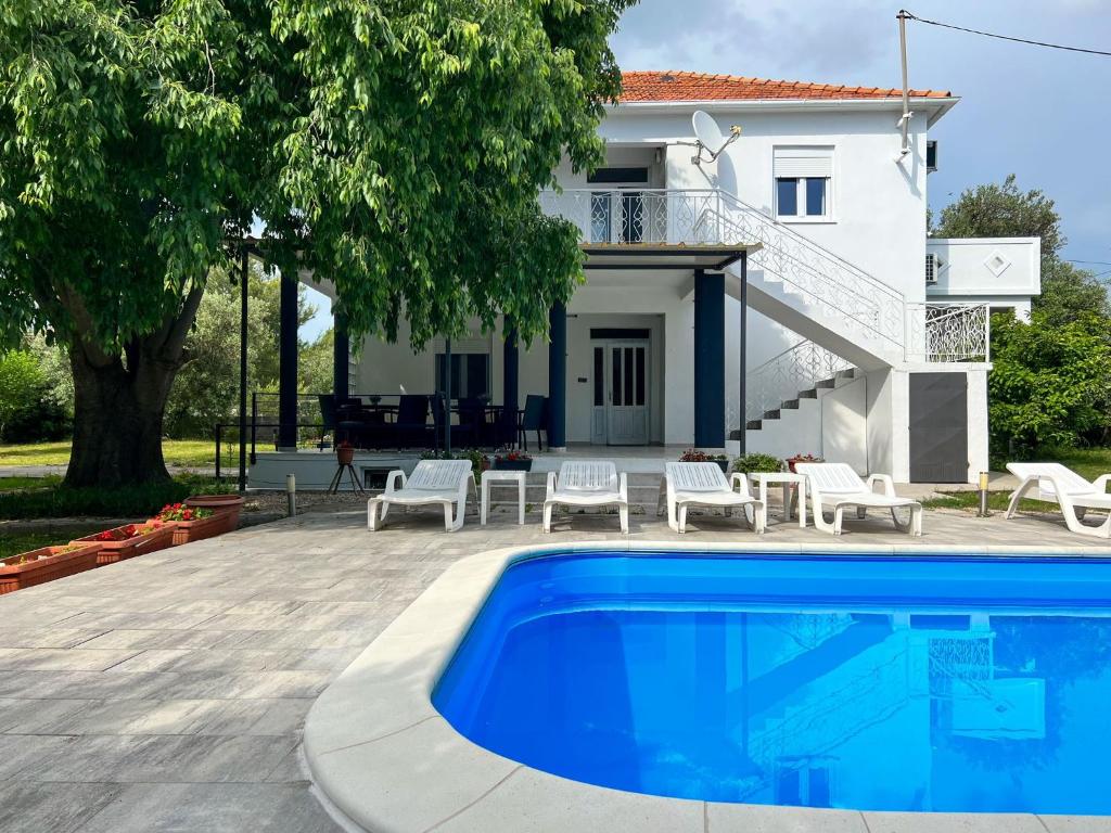 a villa with a swimming pool in front of a house at Apartments Mia in Bibinje