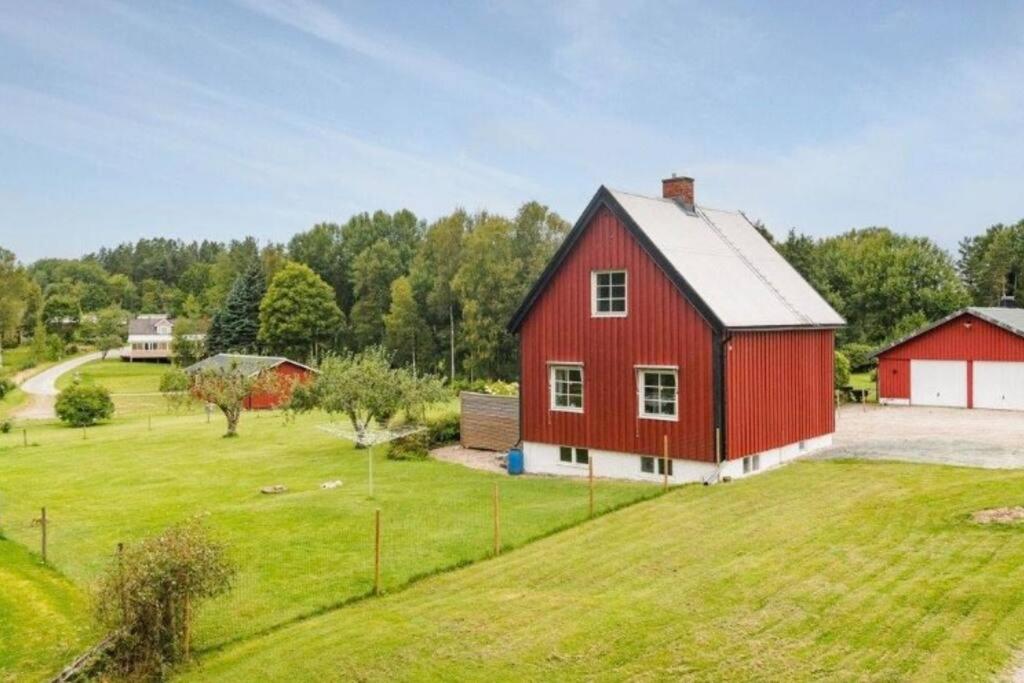 un granero rojo en un campo verde con árboles en Schwedische Landidylle für die ganze Familie, 