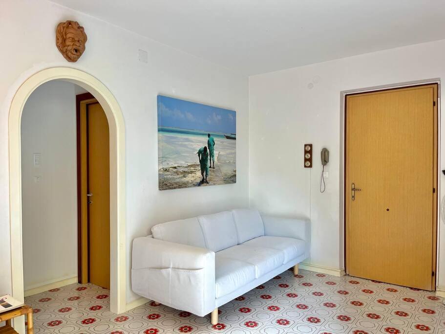 Beach house with private garden and parking في Grado-Pineta: غرفة معيشة بها أريكة بيضاء و لوحة على الحائط