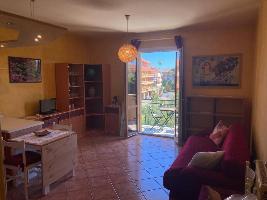 uma sala de estar com um sofá, uma secretária e uma janela em Casa di Ro - coloratissima a 300 metri dal mare em San Bartolomeo al Mare