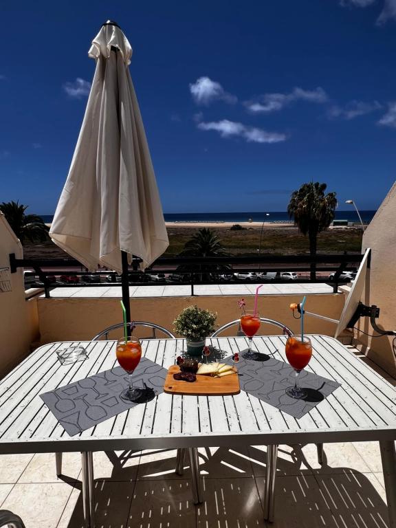 a table with a white umbrella on a balcony at Apartamento perla marina in Morro del Jable