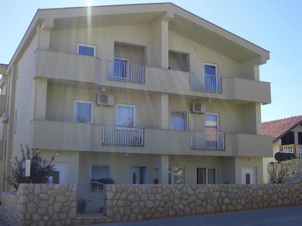 an apartment building with balconies and a stone wall at Apartments Ana in Vir