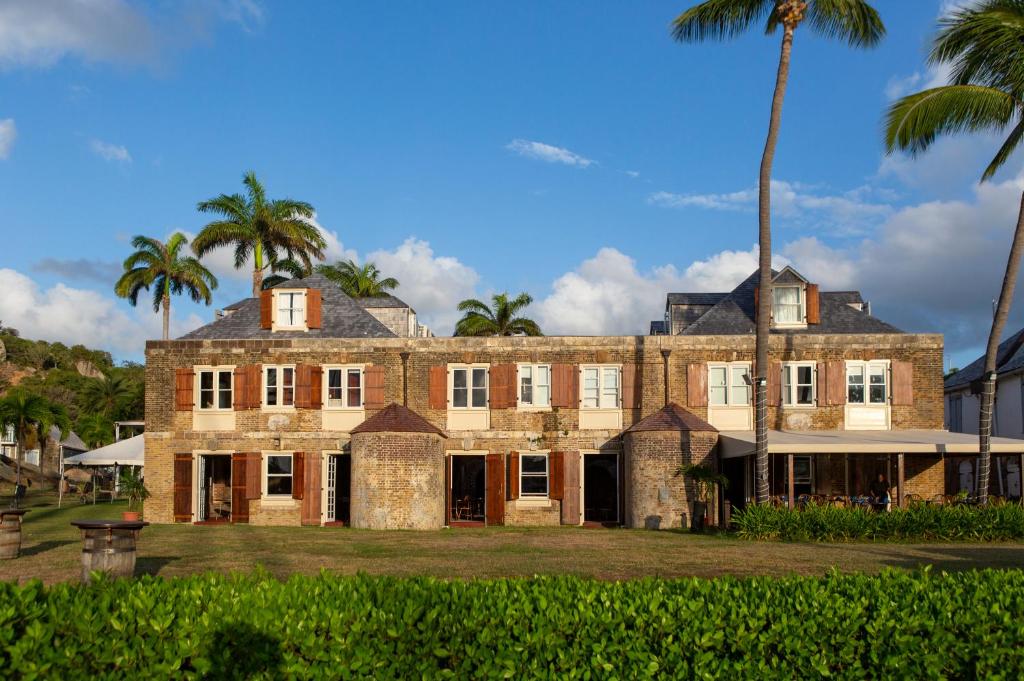 un antiguo edificio de ladrillo con palmeras en el fondo en Copper and Lumber Store Hotel en English Harbour Town