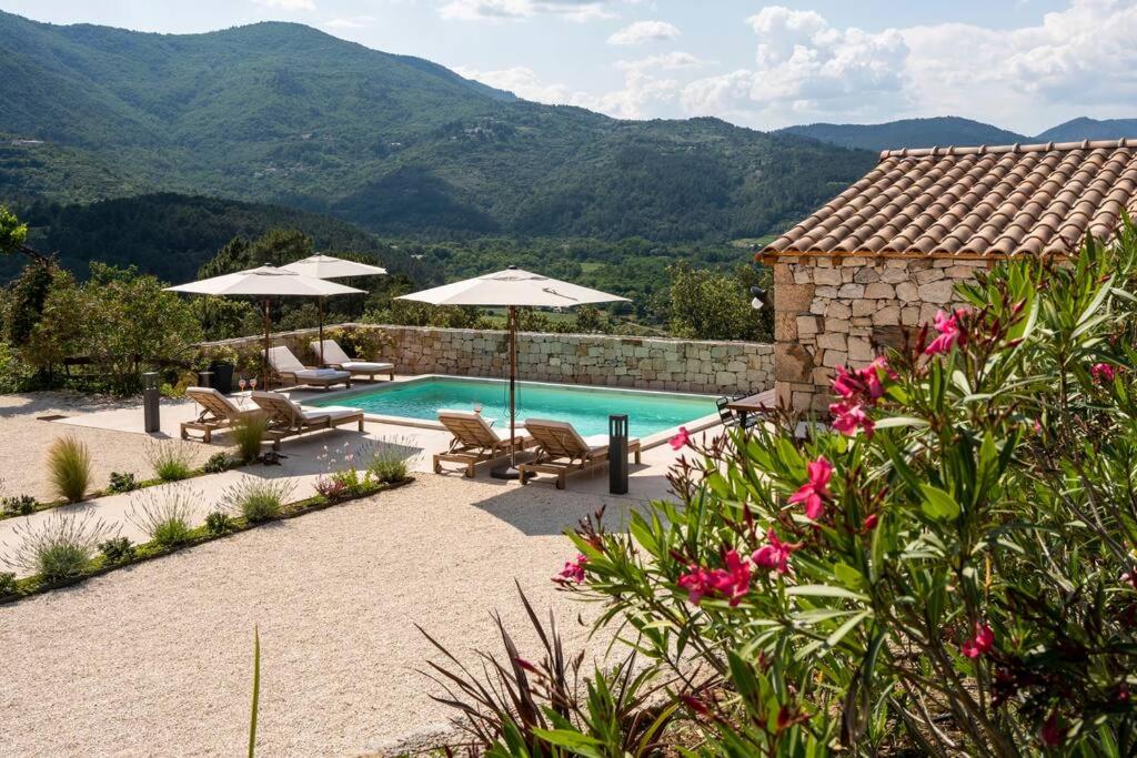 une piscine avec des parasols et des chaises ainsi qu'une maison dans l'établissement villa du Passeron, à Chambonas