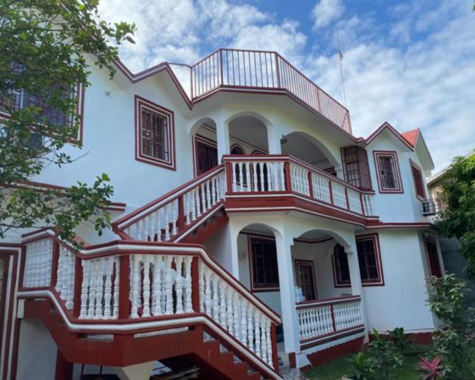 a large white house with a large deck at La Difference Guest House in Cap-Haïtien