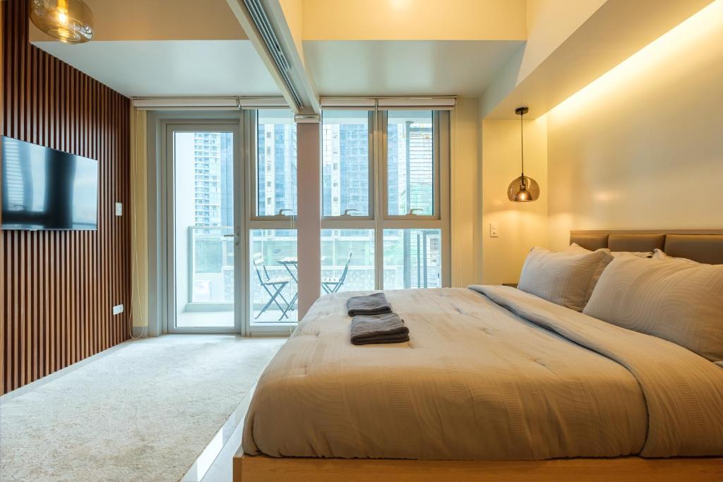een slaapkamer met een groot bed en een groot raam bij Uptown Parksuites Modern Room in Manilla