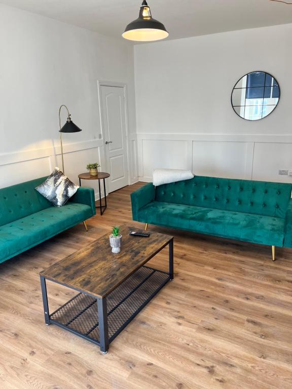 a living room with green couches and a coffee table at Arlos in Blackpool