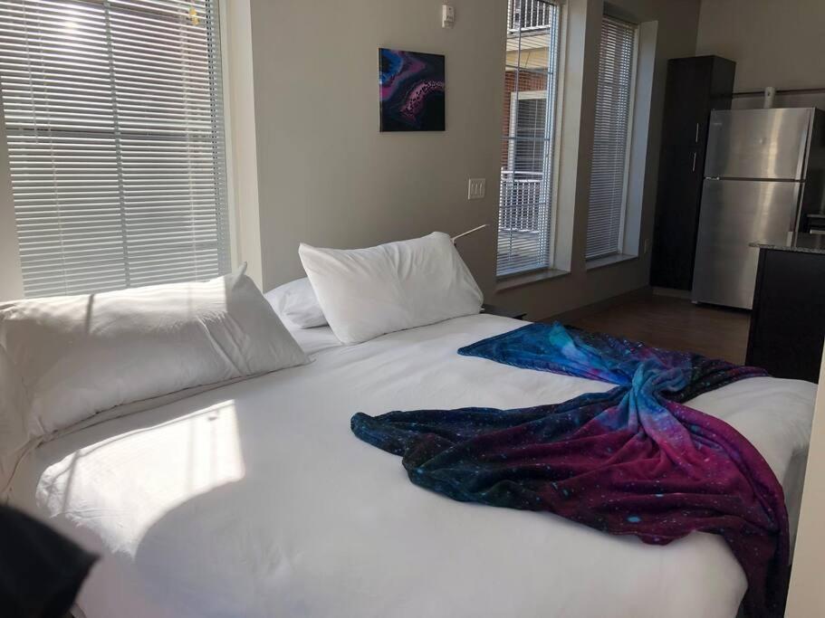 Una cama blanca grande con una manta colorida. en King Size Studio in Heart of Downtown, en Columbus