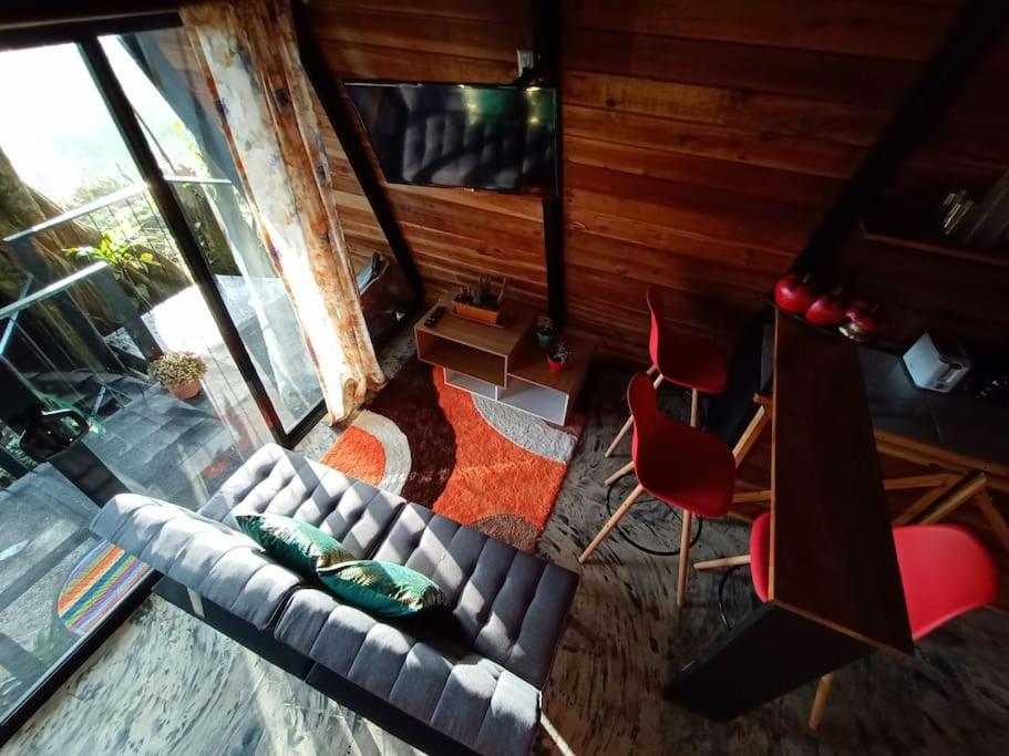 vistas panorámicas a una sala de estar con sofá y sillas en Casa del Árbol (A-Frame) - Ágape del Bosque, en Monteverde