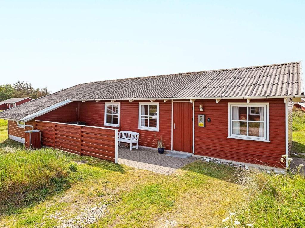 uma casa vermelha com um pátio em frente em Three-Bedroom Holiday home in Frøstrup 1 em Lild Strand
