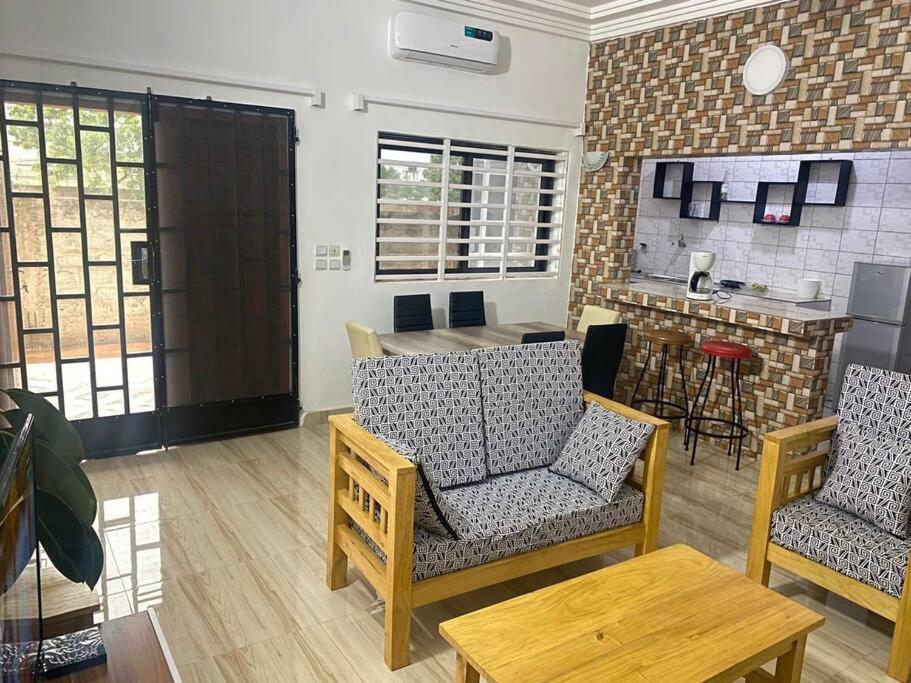sala de estar con 2 sillas y mesa en Appartement climatisé et cozy., en Abomey-Calavi
