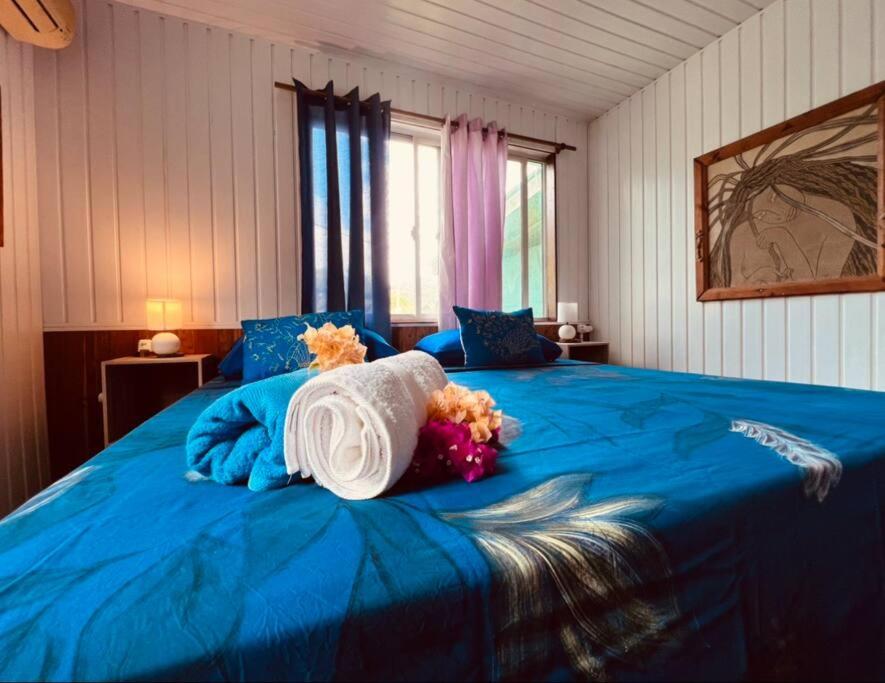 Un dormitorio con una cama azul con flores. en Fare ManuVai, en Haapu