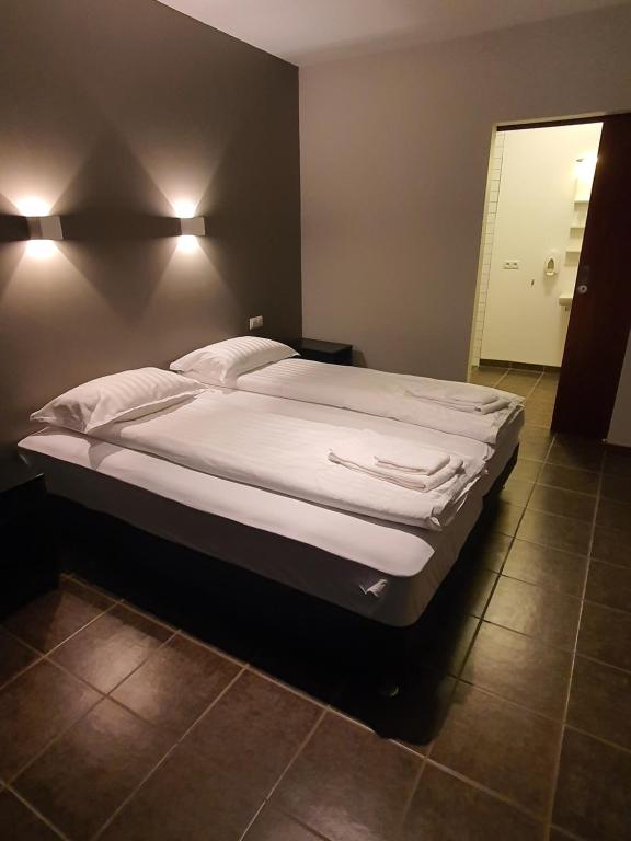 a large bed with white sheets and pillows in a bedroom at Studio 22 in Reyðarfjörður