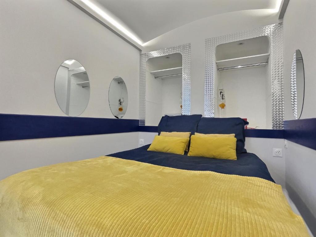 Schlafzimmer mit einem Bett mit gelben Kissen und Spiegeln in der Unterkunft Insolite - Jet Privé - Expérience Cinéma et coc00ning - Moontown in Lunéville