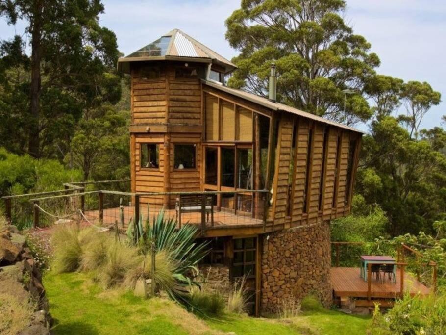 a wooden house on top of a grassy hill at The 'Nook' - Cabin in the Tassie Wilderness! in Ridgeway