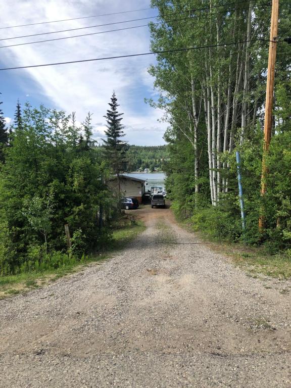 a dirt road with a house in the distance at Porter’s Place in Vanderhoof