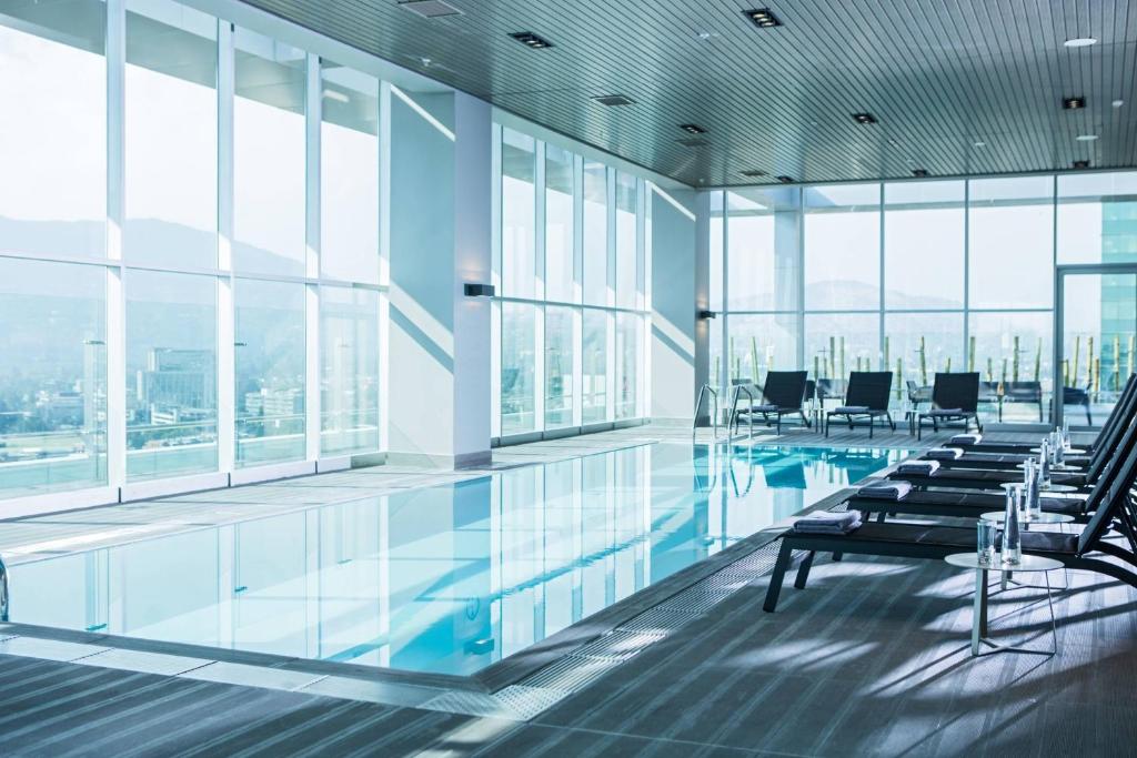 a pool in a building with chairs and windows at Courtyard by Marriott Santiago Las Condes in Santiago